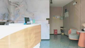 Zona de recepción con pared de mármol, mostrador de recepción, una silla y un basurero.