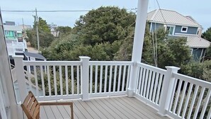 A wooden deck with a white railing, a table, and two chairs.