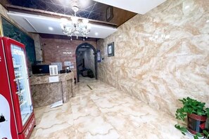 A hotel lobby with a marble floor, a reception desk, a chandelier, and a vending machine. - Atour Hotel Shanghai (Wenhan Road) (Shanghai)