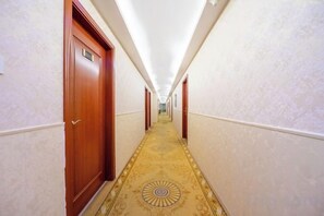 A hotel hallway with wooden doors, a patterned carpet, and a ceiling light. - Atour Hotel Shanghai (Wenhan Road) (Shanghai)