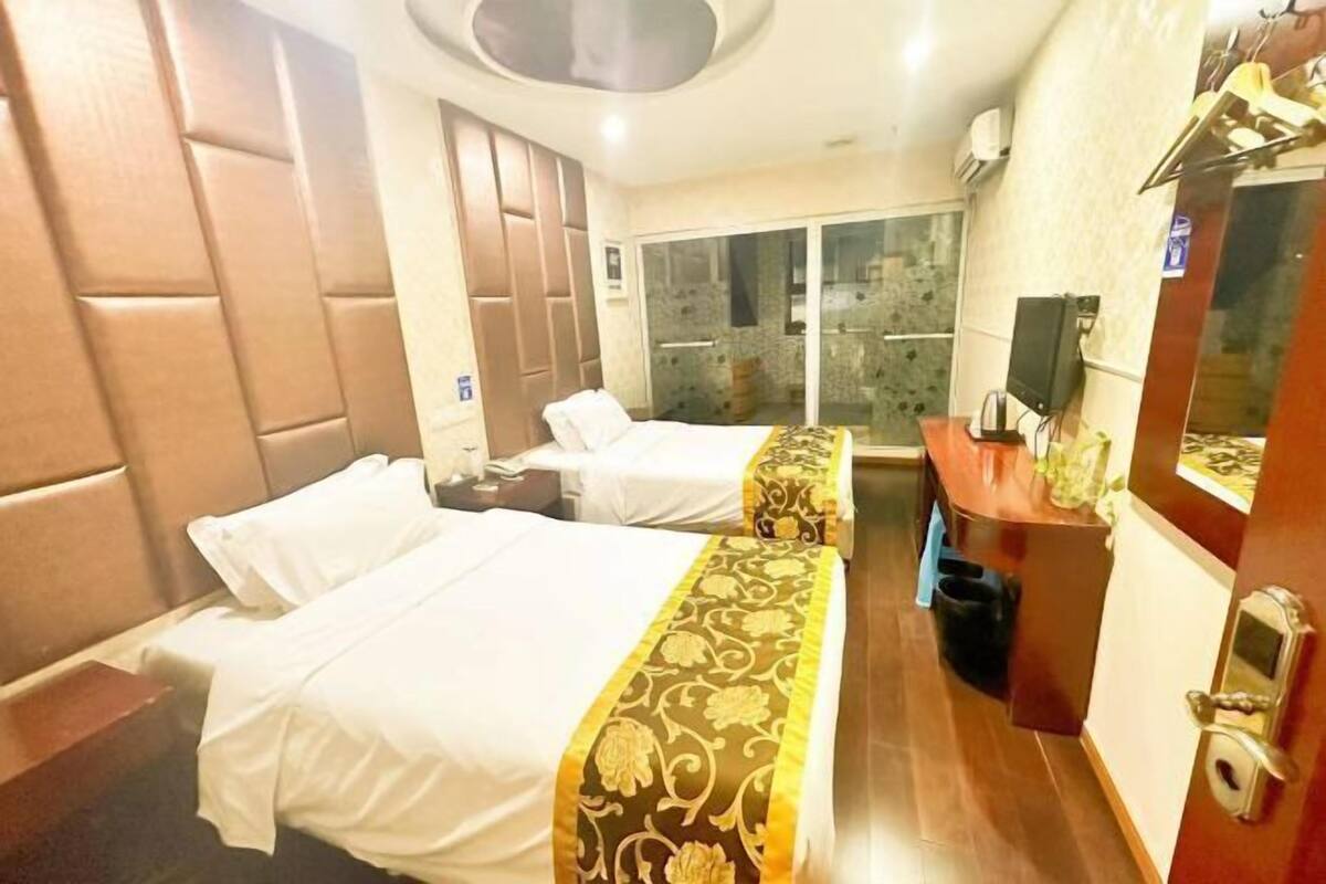 Une chambre d’hôtel avec deux lits, un bureau, un miroir et une porte coulissante donnant sur un balcon.