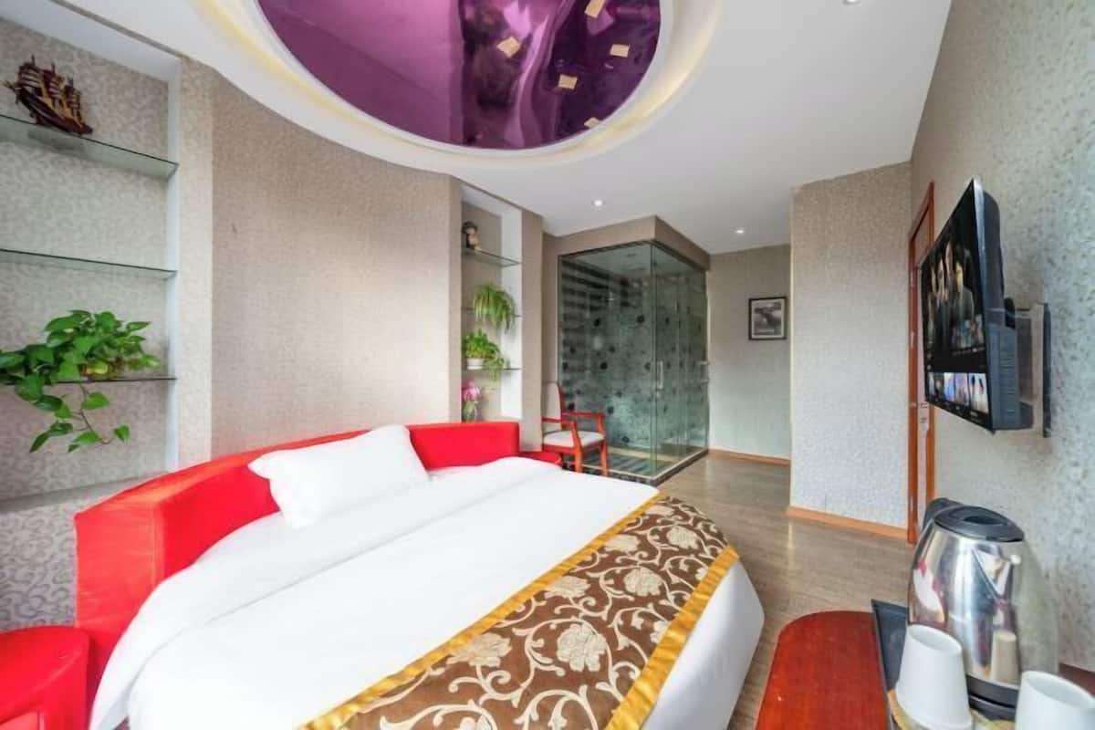 Une chambre d’hôtel équipée d’un lit, d’une télévision, d’une machine à café et d’une porte vitrée donnant sur un balcon.