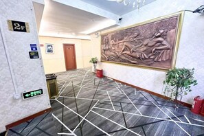 A hotel lobby with a patterned carpet, a large wall-mounted sculpture, and a door in the background. - Atour Hotel Shanghai (Wenhan Road) (Shanghai)