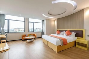 A hotel room with a large bed, a desk, a chair, a small table, and a view of the city through large windows. - Shankee Express Hotel (Beijing Miyun Guoyuan) (Beijing)