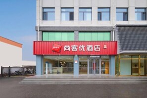 A hotel with a red signboard, a glass entrance, and a modern facade. - Shankee Express Hotel (Beijing Miyun Guoyuan) (Beijing)