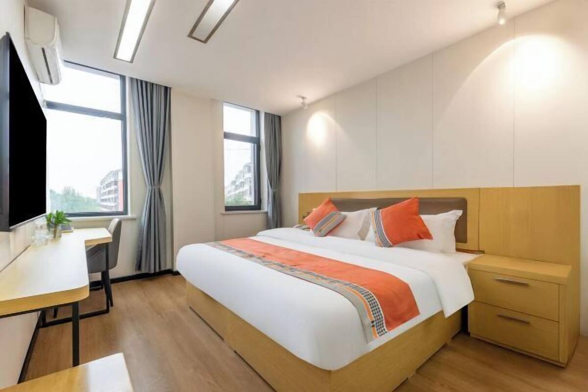 A hotel room with a bed, bedside table, desk, and a TV.