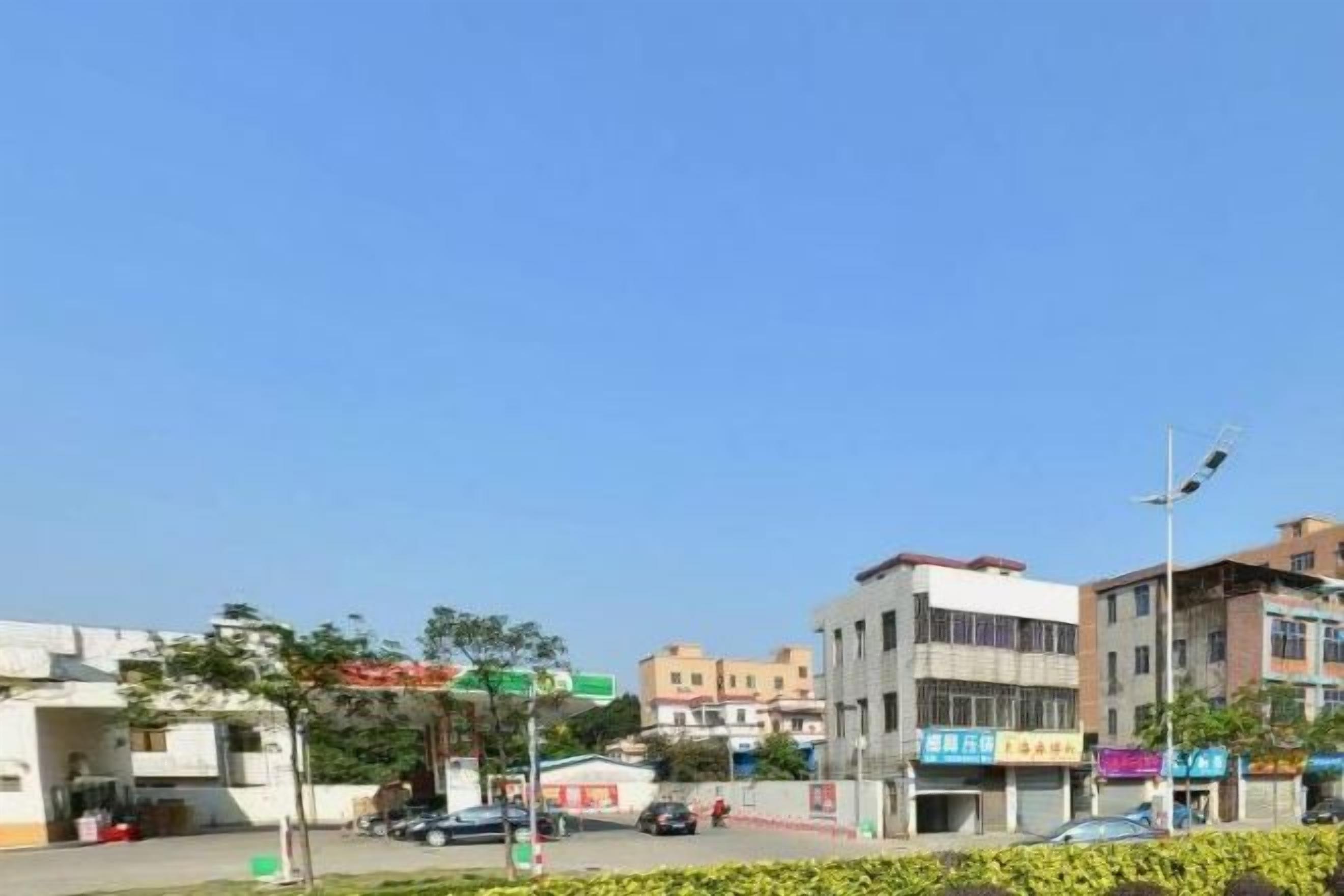 A street view with buildings, a clear sky, and a few cars.