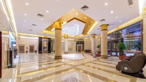 A spacious lobby with a polished marble floor, large columns, and a massage chair. - Guangbin Mantiao Hotel (Foshan Lishui Wanli Plaza) (Foshan)