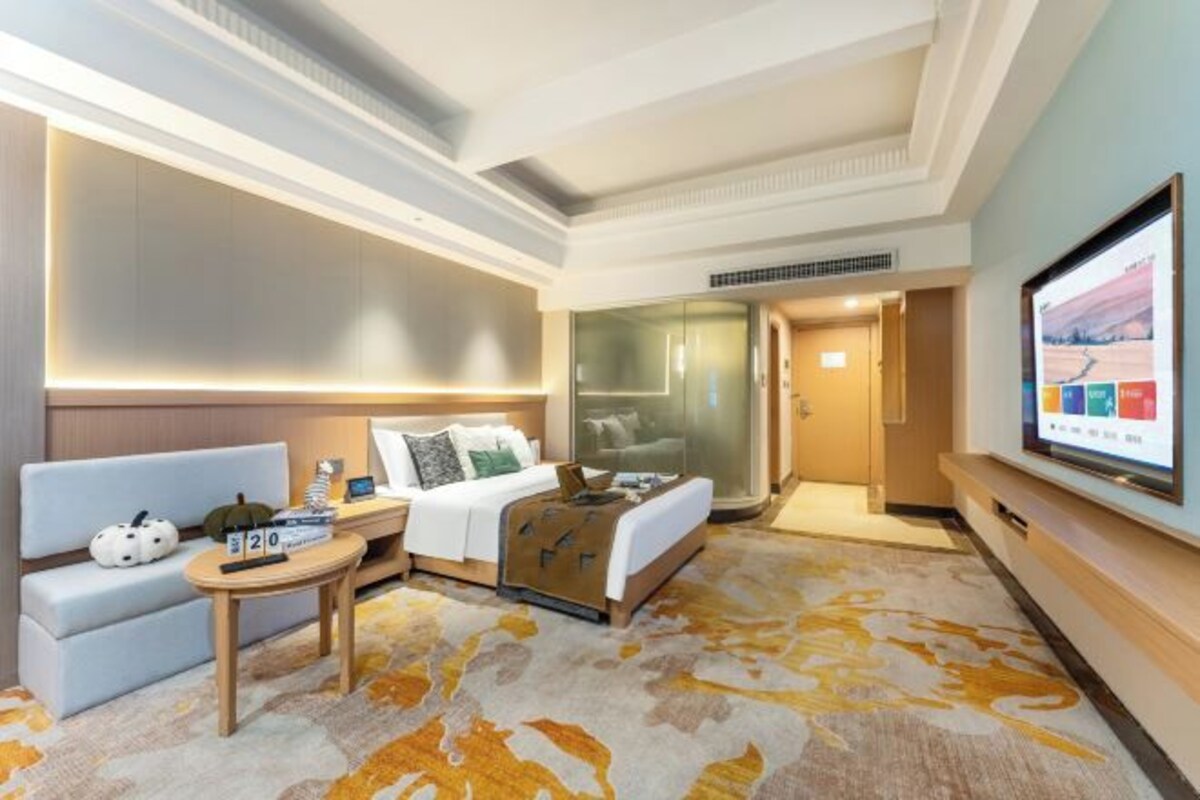 A hotel room with a bed, a sofa, a small table, and a TV.