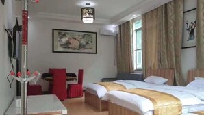 A hotel room with two beds, a desk, and a chair. There is a painting on the wall and a window with curtains. - Puyuan Xiangu Hotel (Chishui)