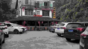 A street view with parked cars and a building with a sign. - Puyuan Xiangu Hotel (Chishui)