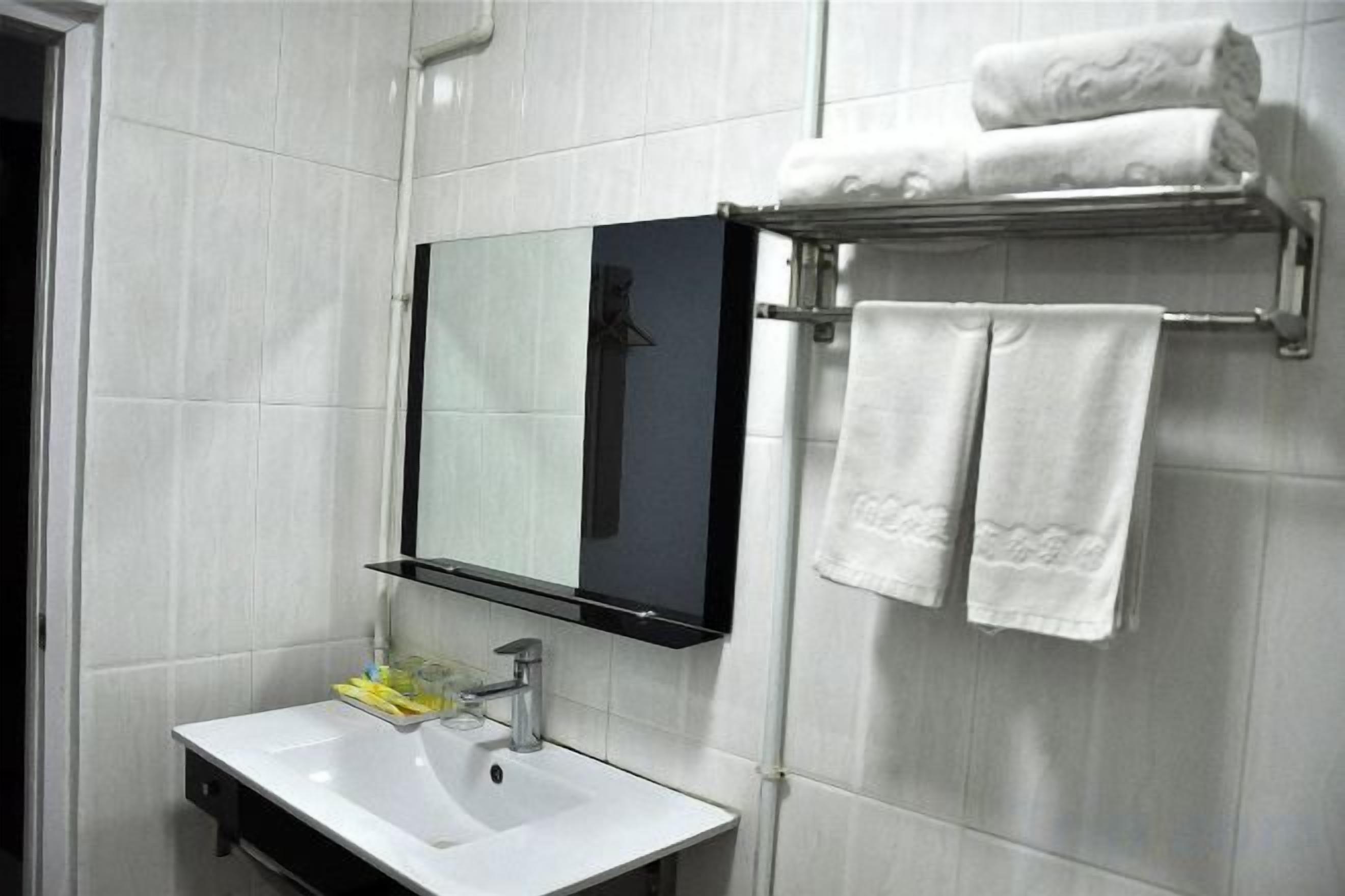 A bathroom with a white sink, a mirror, and a towel rack with towels.