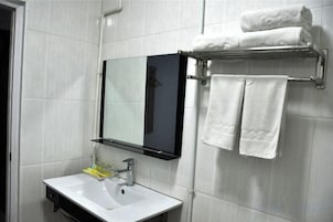 A bathroom with a white sink, a mirror, and a towel rack with towels.