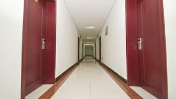A long, narrow hallway with two red doors on either side and a white tiled floor.