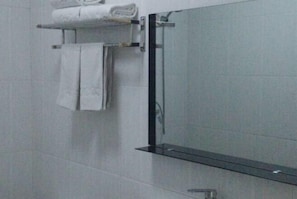 A bathroom with white tiled walls, a glass shower enclosure, and a towel rack with folded towels. - Yangguang Express Hotel (Yinan)