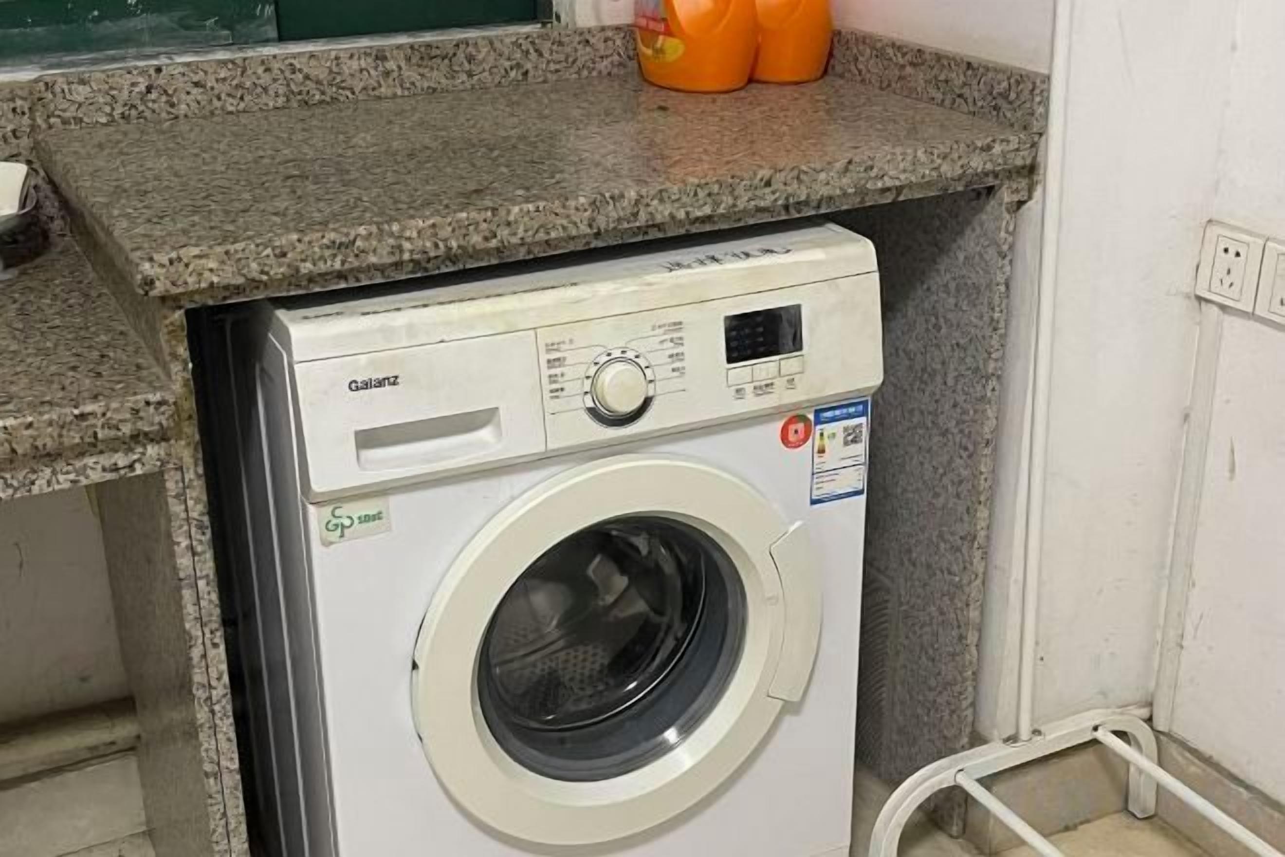A front-loading washing machine with a control panel, a detergent dispenser, and a label indicating energy efficiency.