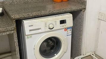 A front-loading washing machine with a control panel, a detergent dispenser, and a label indicating energy efficiency.