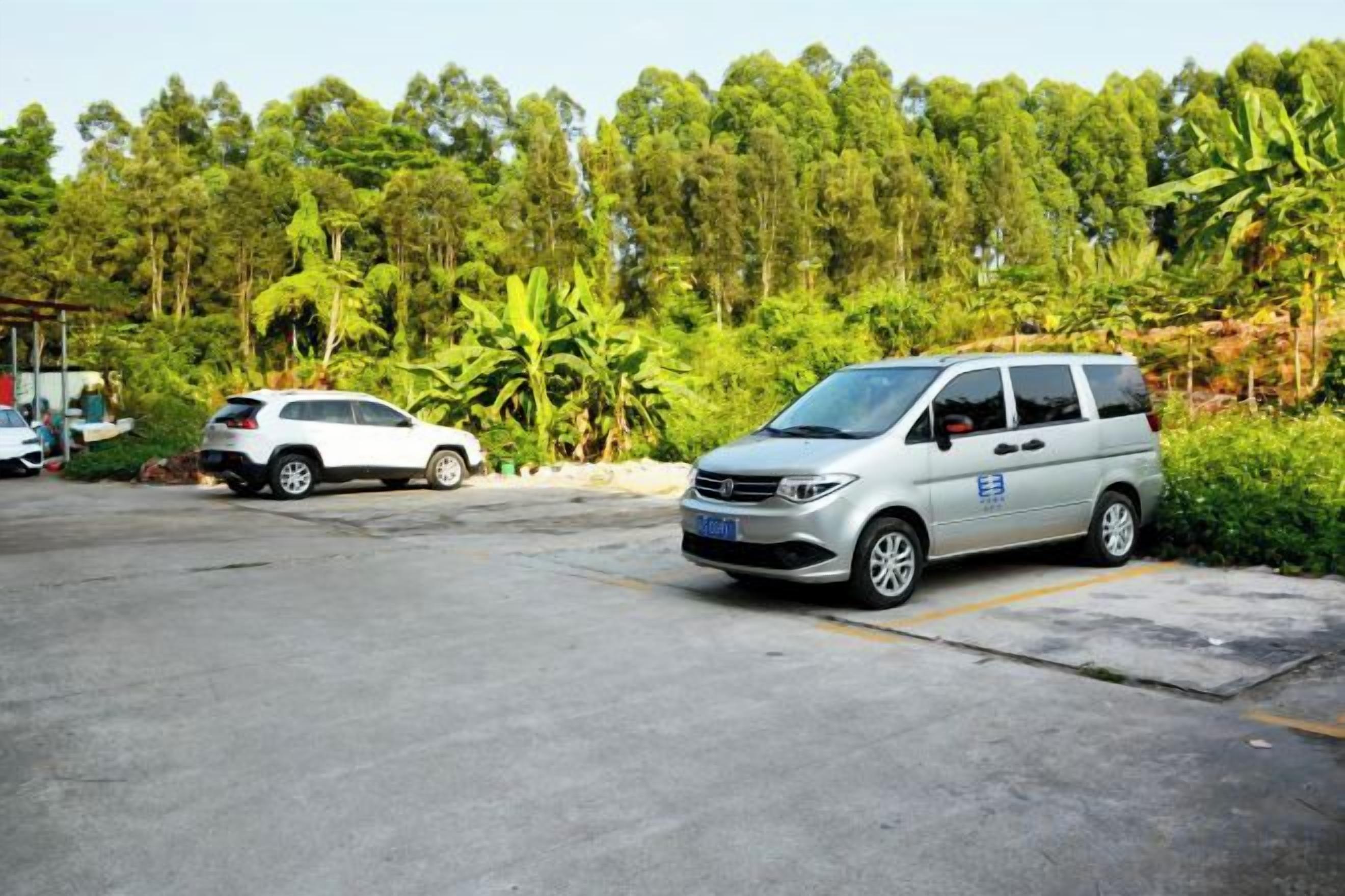 Un espace de stationnement où se trouvent une voiture blanche et un fourgon argenté.