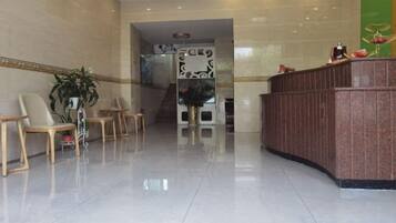 A reception area with a reception desk, several chairs, and a staircase leading to an upper floor.