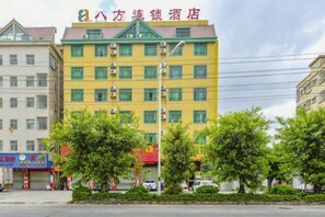 A multi-story hotel with a green roof, multiple windows, and a visible entrance.