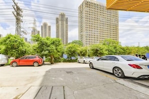 A parking lot with cars, trees, and tall buildings in the background. - 8 Inn (Dongguan)