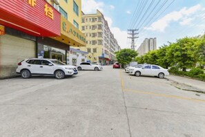 A street with parked cars and buildings with commercial signs. - 8 Inn (Dongguan)