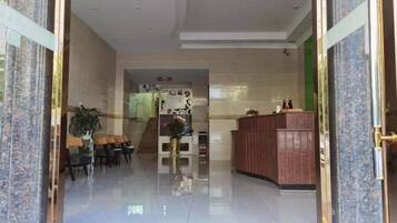 A hotel lobby with a reception desk, seating area, and a plant.