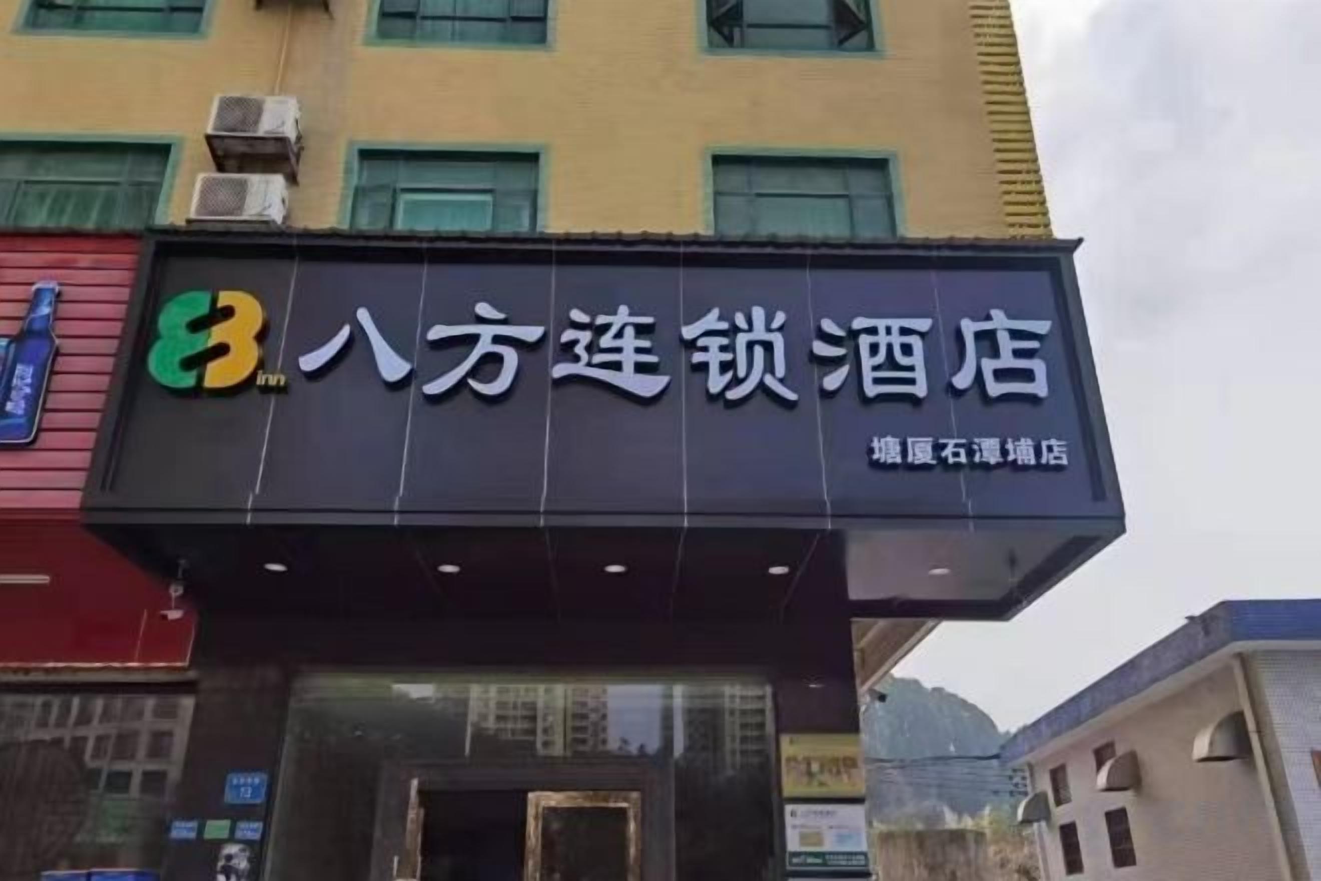 A hotel sign with the name '八方连锁酒店' and a logo on the left.