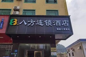 A hotel sign with the name '八方连锁酒店' and a logo on the left. - 8 Inn (Dongguan)