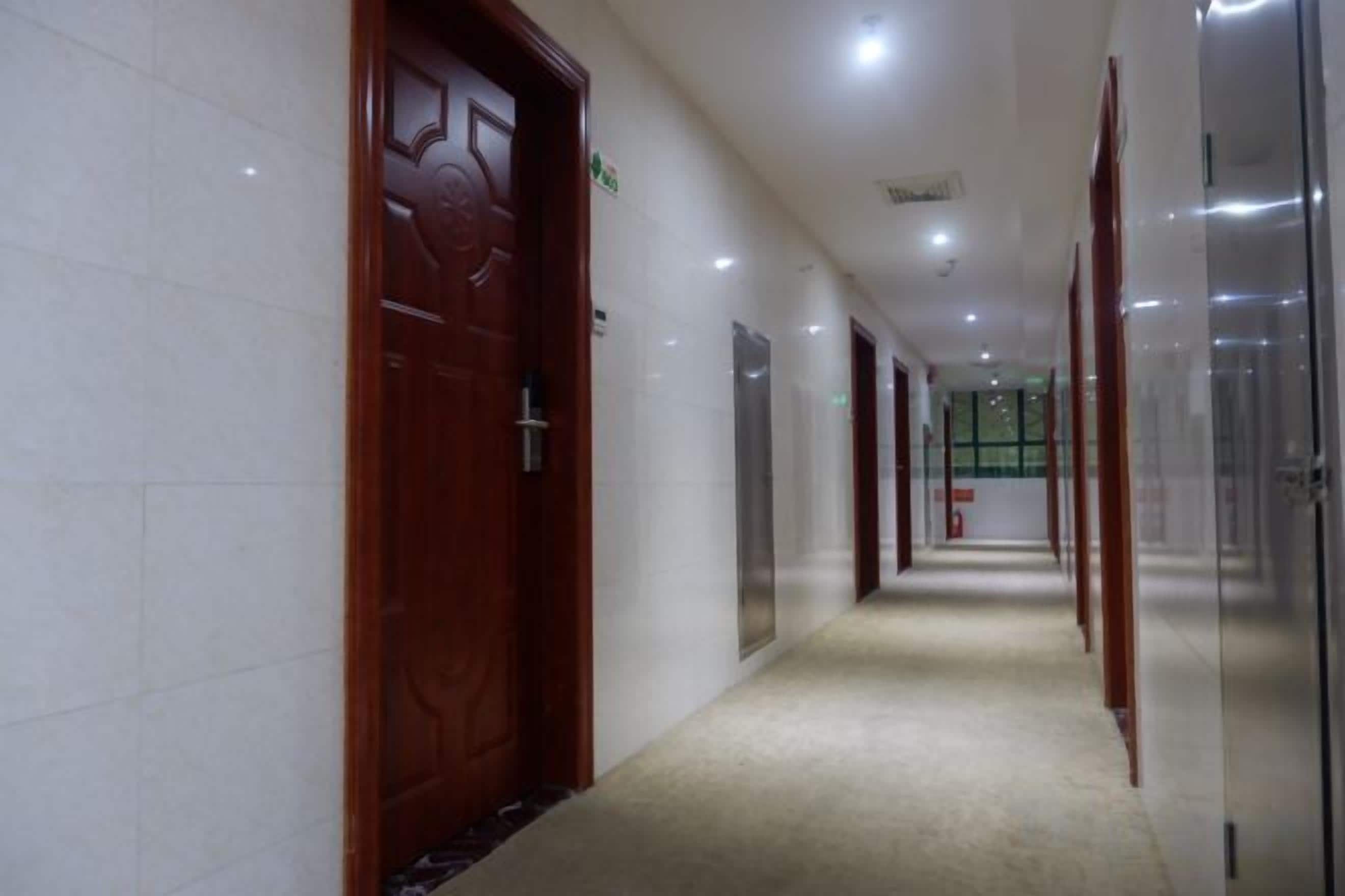 A corridor with doors, a carpeted floor, and glass walls.