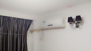 Ein Zimmer mit einem Bett, einem Vorhang, einer Klimaanlage und zwei Wandleuchten.