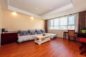 A living room with a sofa, a coffee table, a dining table with chairs, and a cabinet. - Korla Apricot Business Hotel (Korla)