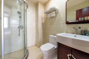 A modern bathroom with a glass-enclosed shower, a white toilet, and a vanity with a mirror and toiletries. - Korla Apricot Business Hotel (Korla)