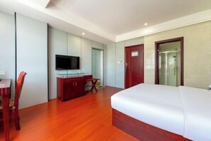 Een hotelkamer met een bed, een bureau met stoel, een televisie en een douche.