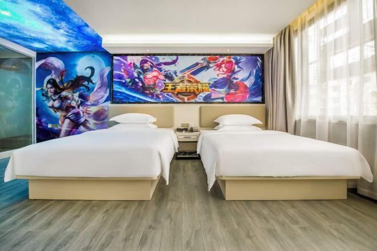 A hotel room with two beds, a large wall mural, and a wooden floor.