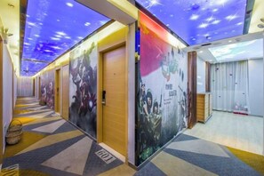 A hotel corridor with doors, a reception desk, and a ceiling with a starry design.