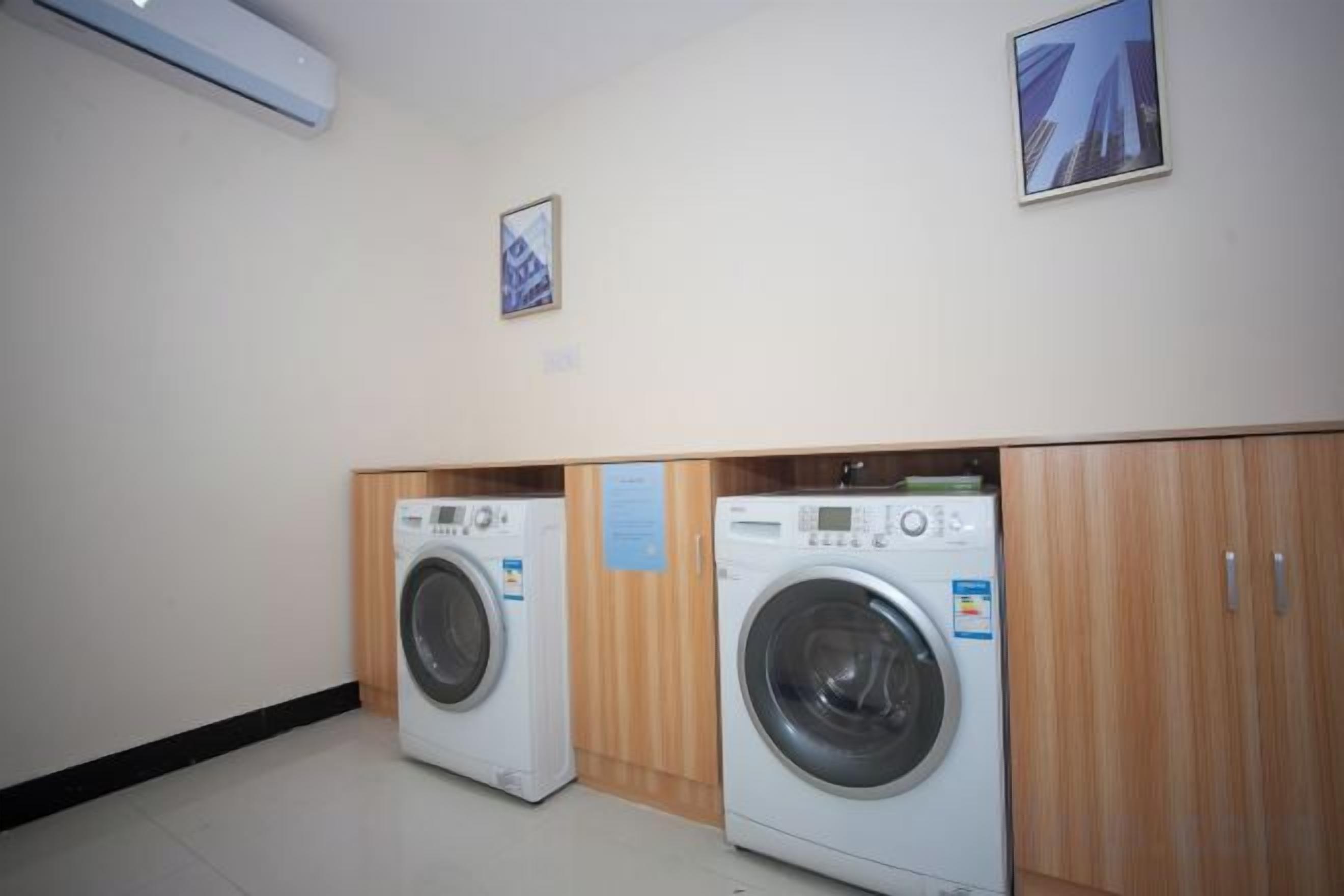 A laundry room with two washing machines, wooden cabinets, and a wall-mounted air conditioner.
