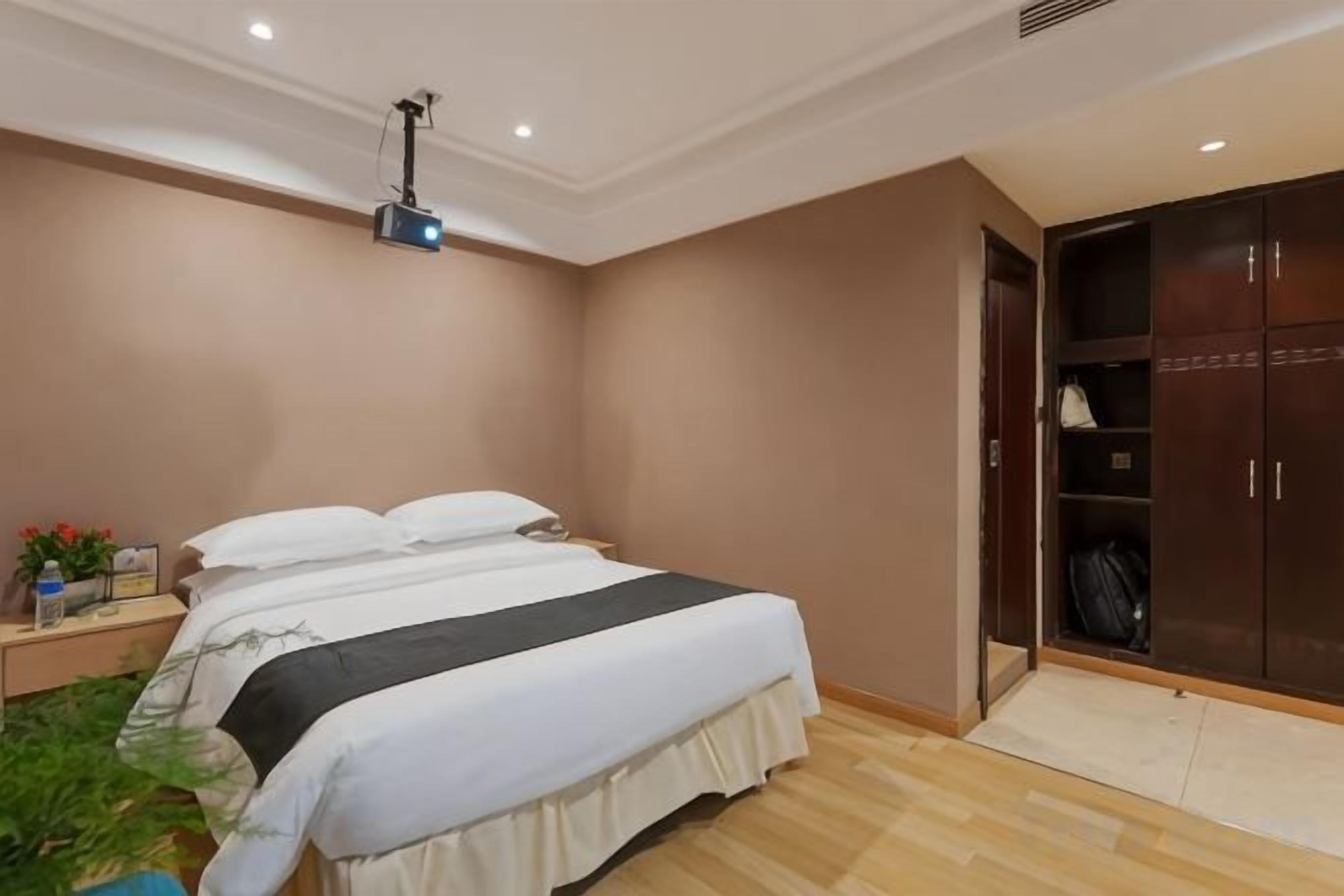 A bedroom with a bed, a wardrobe, and a projector on the ceiling.