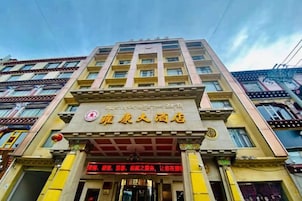 A hotel with a traditional architectural style, featuring a prominent entrance with a red awning and a signboard.