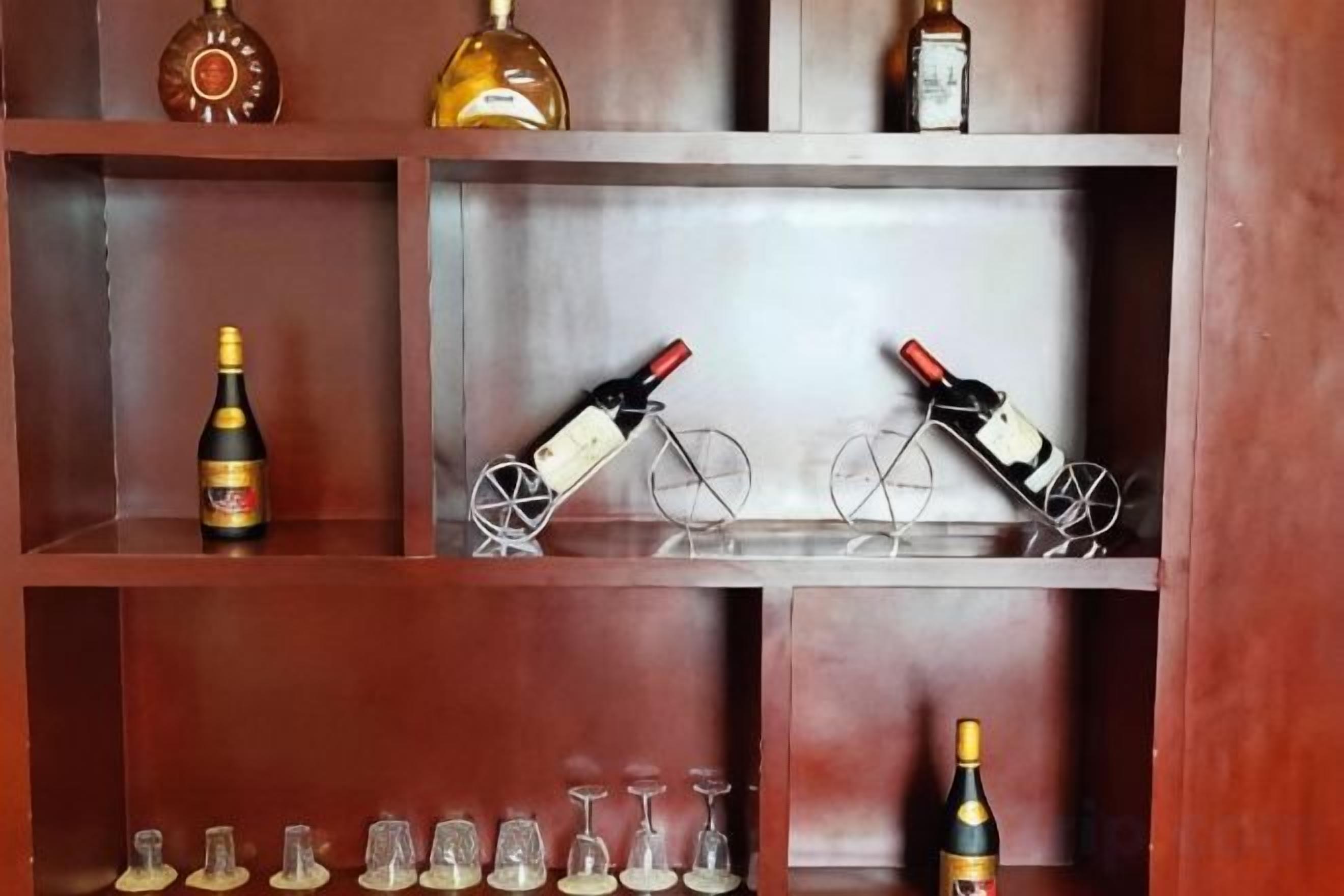 A wooden shelf with various bottles and glasses.