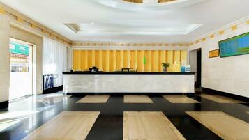 Eine Hotelhalle mit einer Rezeption, einem Check-in-Schalter und einem großen Fenster links.