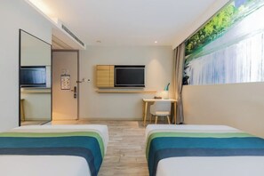 Een hotelkamer met twee bedden, een bureau, een televisie en een groot raam met een schilderij.