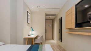 A hotel room with a bed, a desk with a chair, a TV mounted on the wall, and a door leading to another room. - Homeinn Selected Hotel (Nanjing Xiongzhou Subway Station Jinning Plaza) (Nanjing)