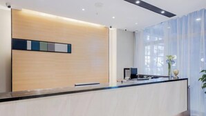A modern reception desk with a light wood finish, a black countertop, and a glass partition. - Homeinn Selected Hotel (Nanjing Xiongzhou Subway Station Jinning Plaza) (Nanjing)
