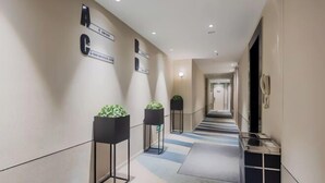 A hotel corridor with directional signs, potted plants, and a tiled floor. - Homeinn Selected Hotel (Nanjing Xiongzhou Subway Station Jinning Plaza) (Nanjing)