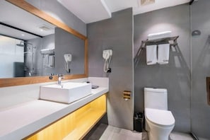 A modern bathroom with a white sink, a mirror, a toilet, and a towel rack.