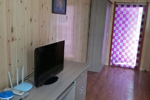 A room with a television on a wooden cabinet, a door with a checkered pattern, and a hallway. - Moerdaoga Juyuan Senlin Zhijia Hotel (Ergun)