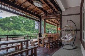 A wooden deck with benches and a hanging chair overlooking a forested area. - Yunshang Zhulin Yaju · Swimming Pool Resort Minshuku (Anji)