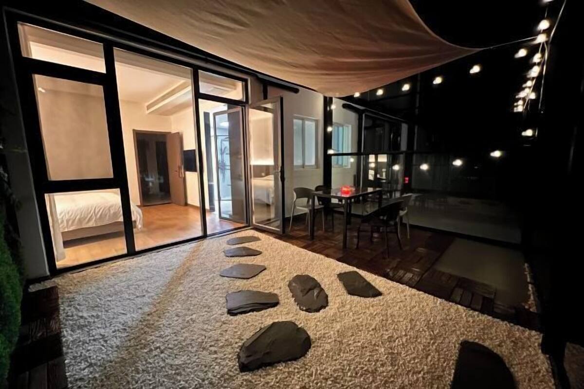 Ein modernes Interieur mit einer Glastür, die zu einem Schlafzimmer führt, einem Essbereich mit Tisch und Stühlen sowie einem Teppichboden mit Steinweg.