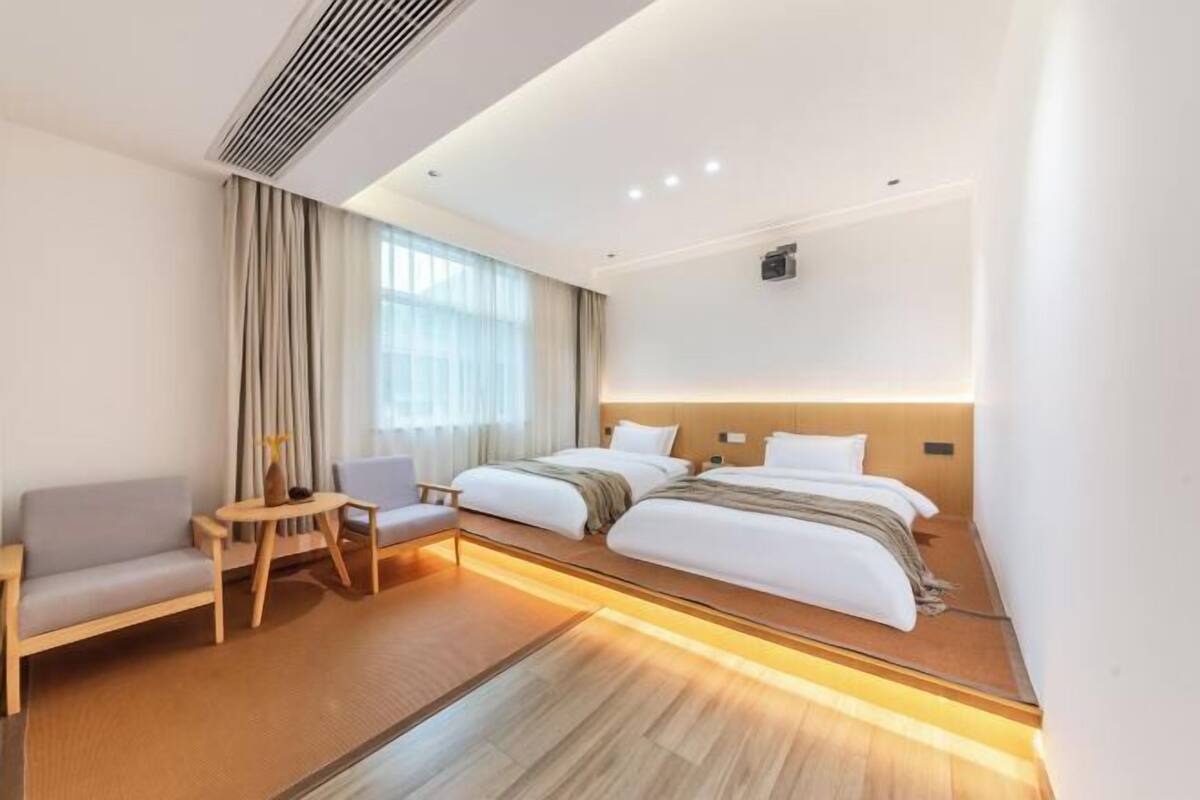 Ein Hotelzimmer mit Bett, Sofa, kleinem Tisch und einem Fenster mit Vorhängen.